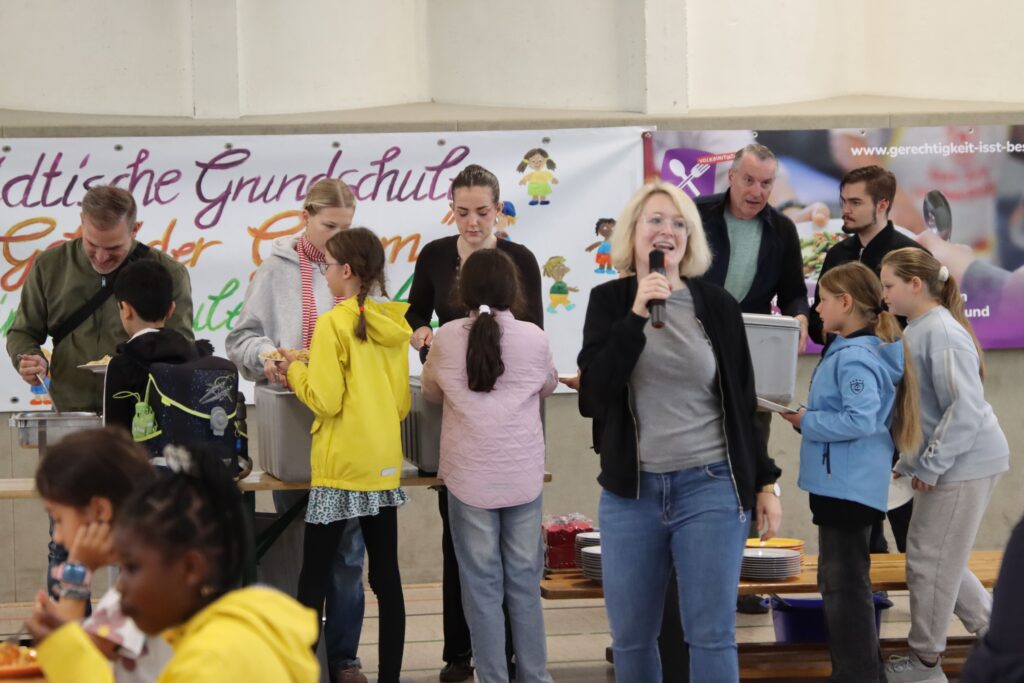 Schülerinnen und Schüler an der Essensausgabe in einer Turnhalle